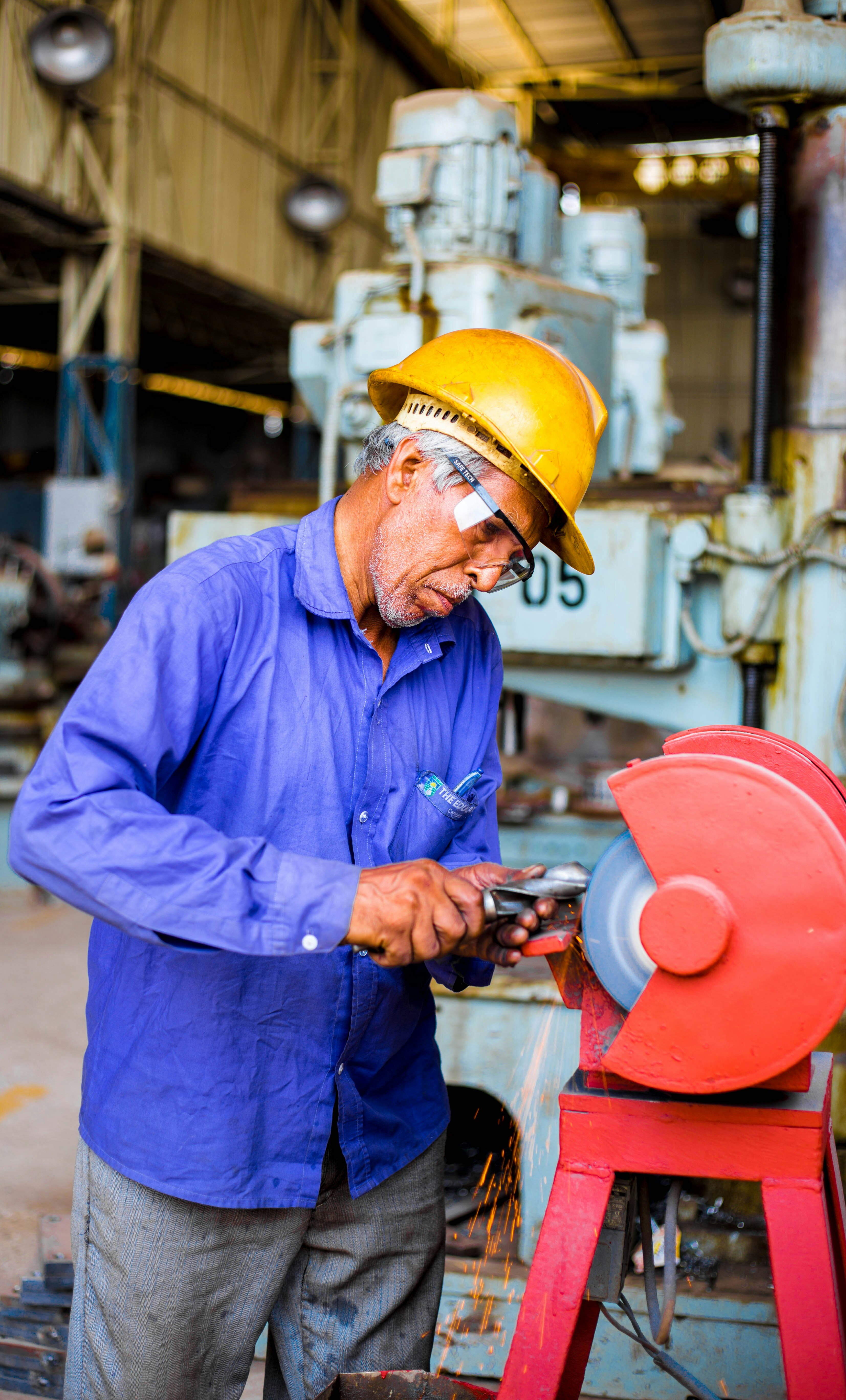 Older factory worker sharpens tool